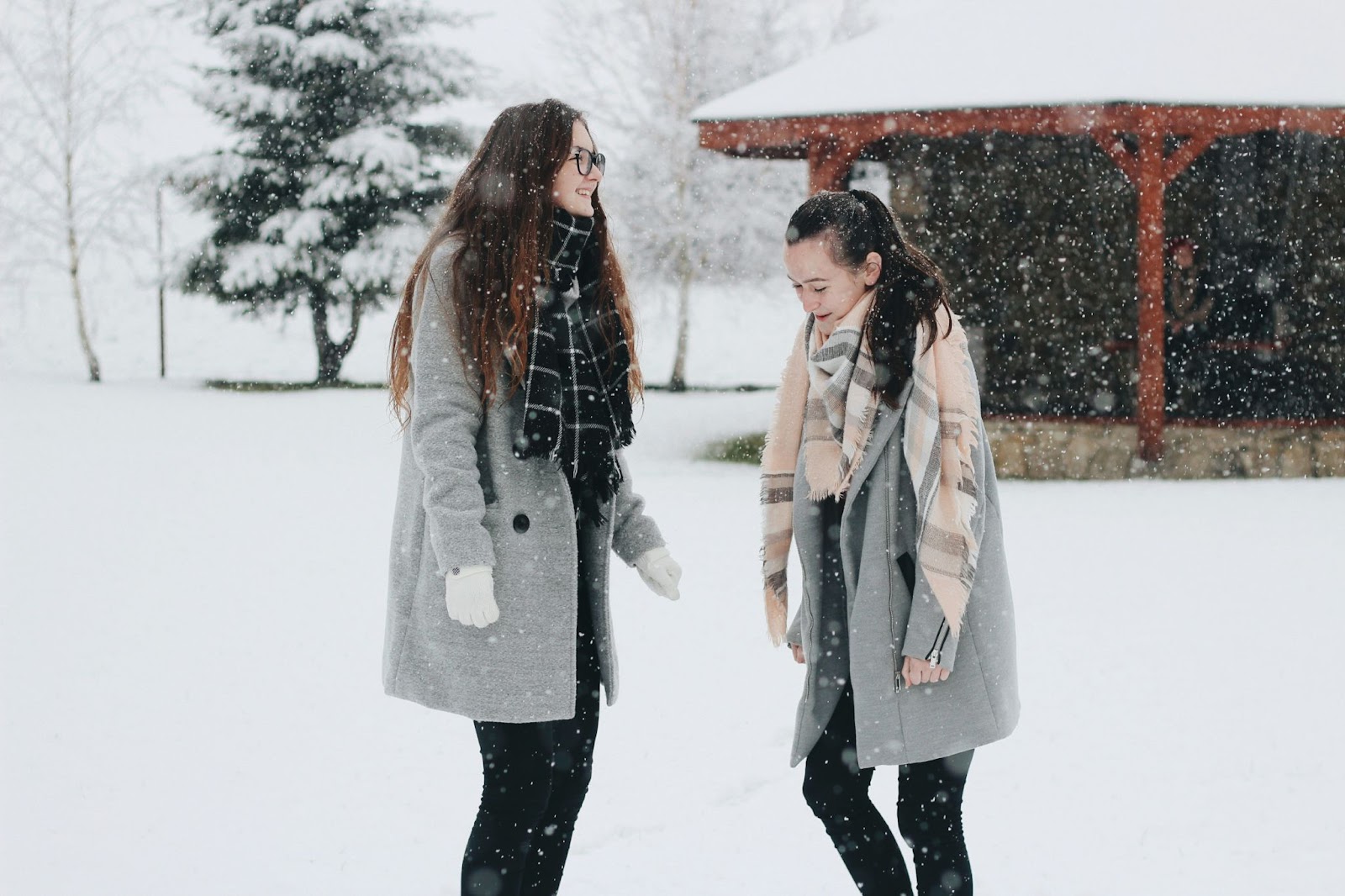 two friends smiling happily while walking through a snowy day